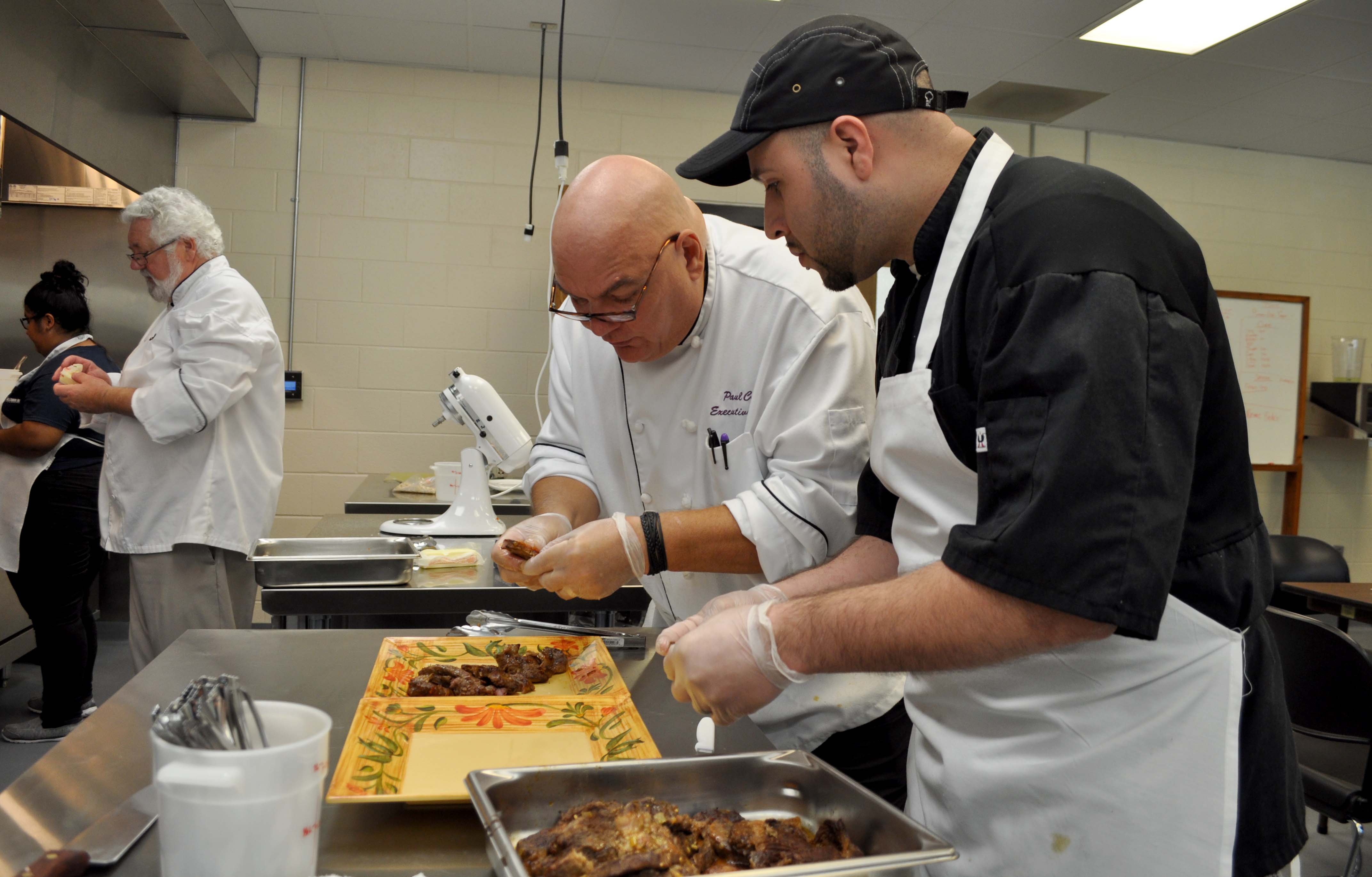 Cooking instructor shows student how to plate food.