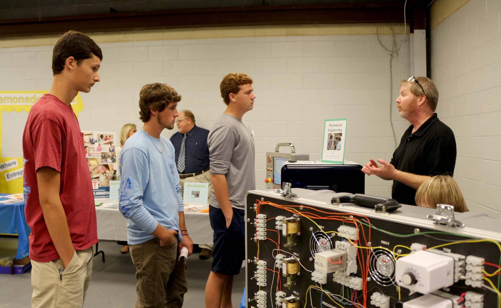 Three students talk to Mechanical Engineering Instructor Matthew Lincoln.