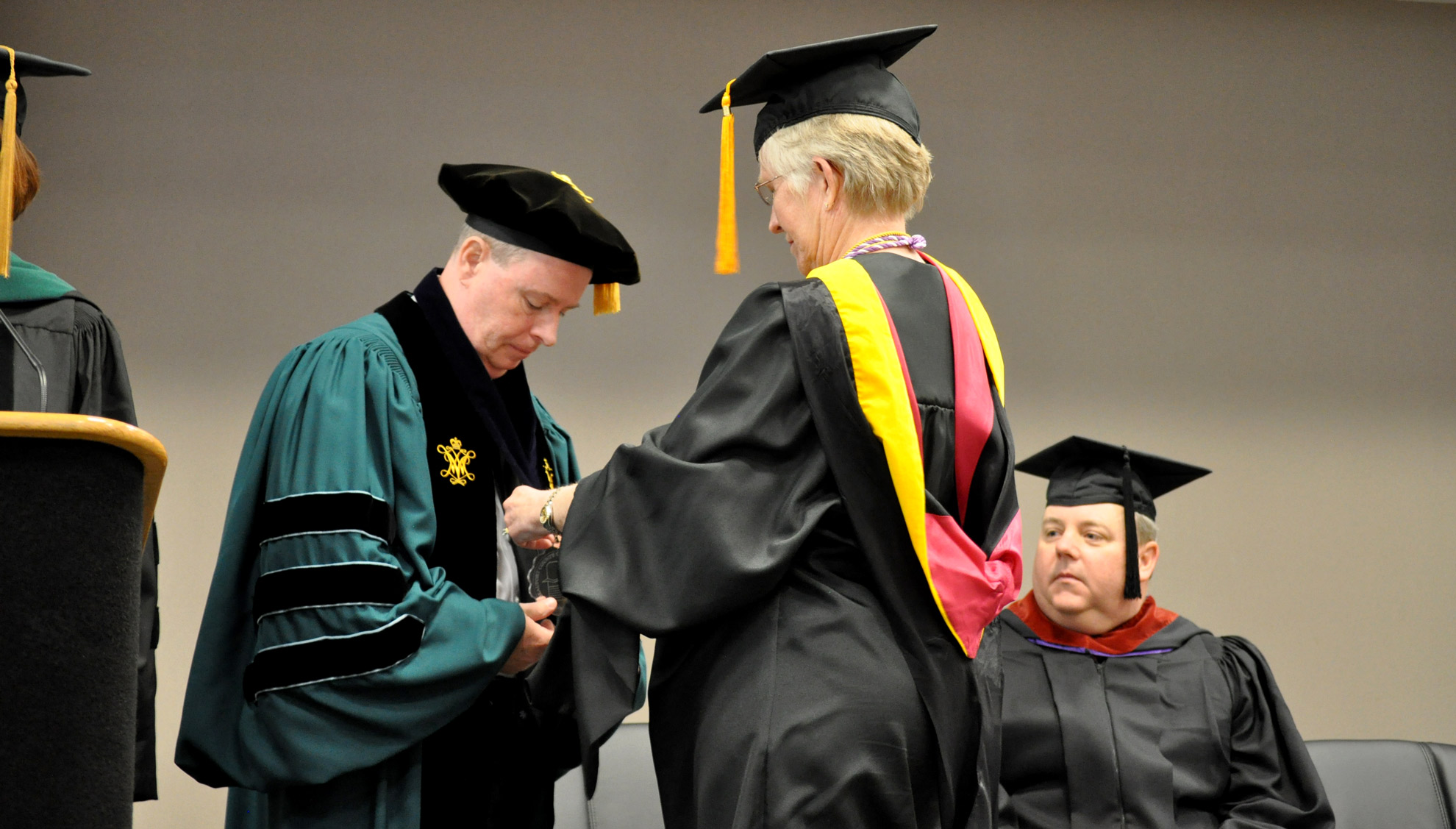 Col. Kathy Simpson places a medalion on President Loope.