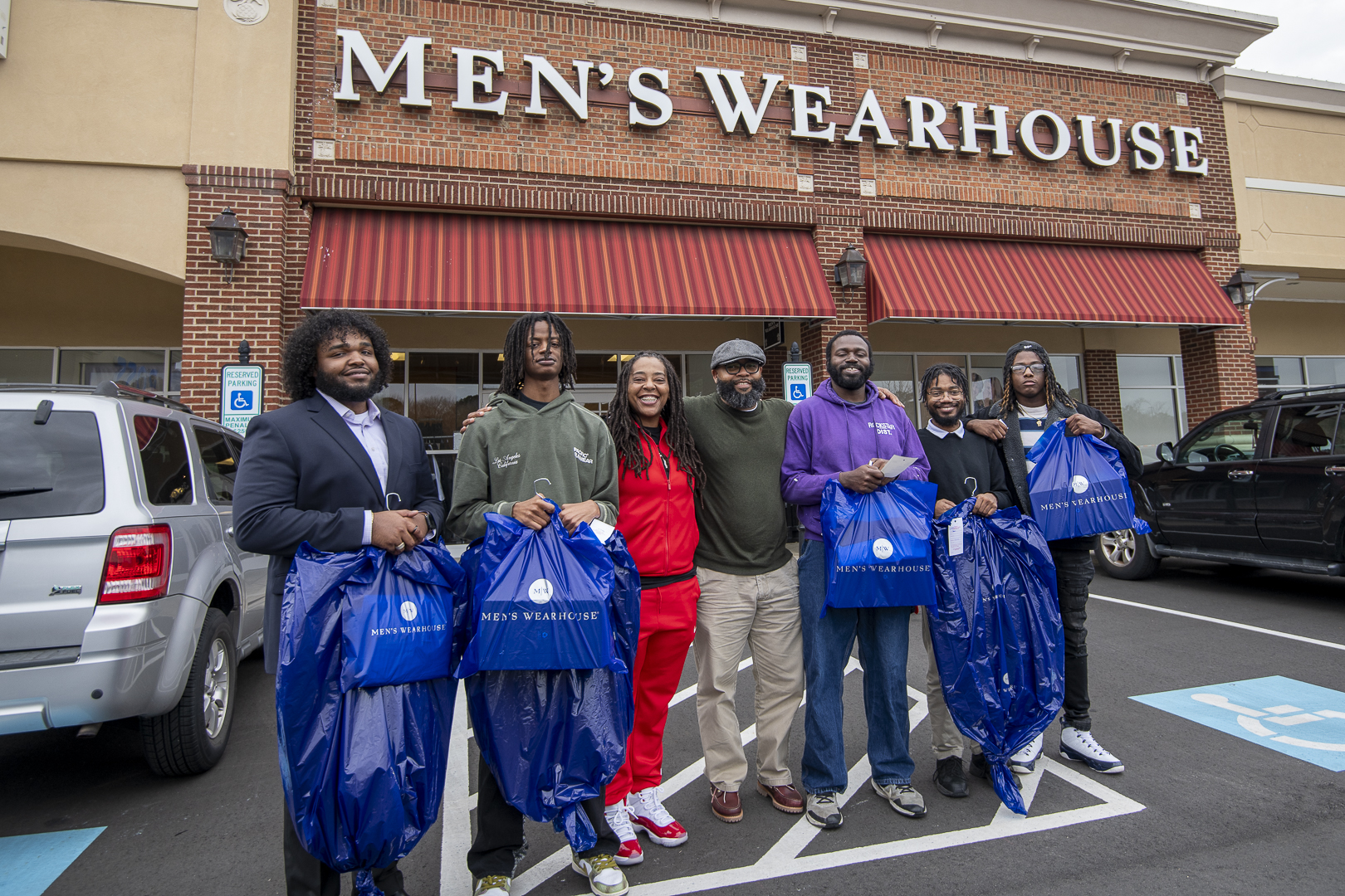 people holding bags in front of Mens Wearhouse