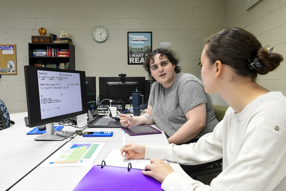 two people talking with a computer screen