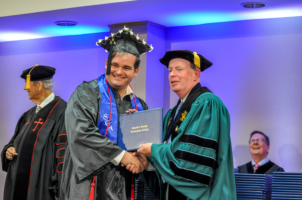 a graduate shaking hands with another person