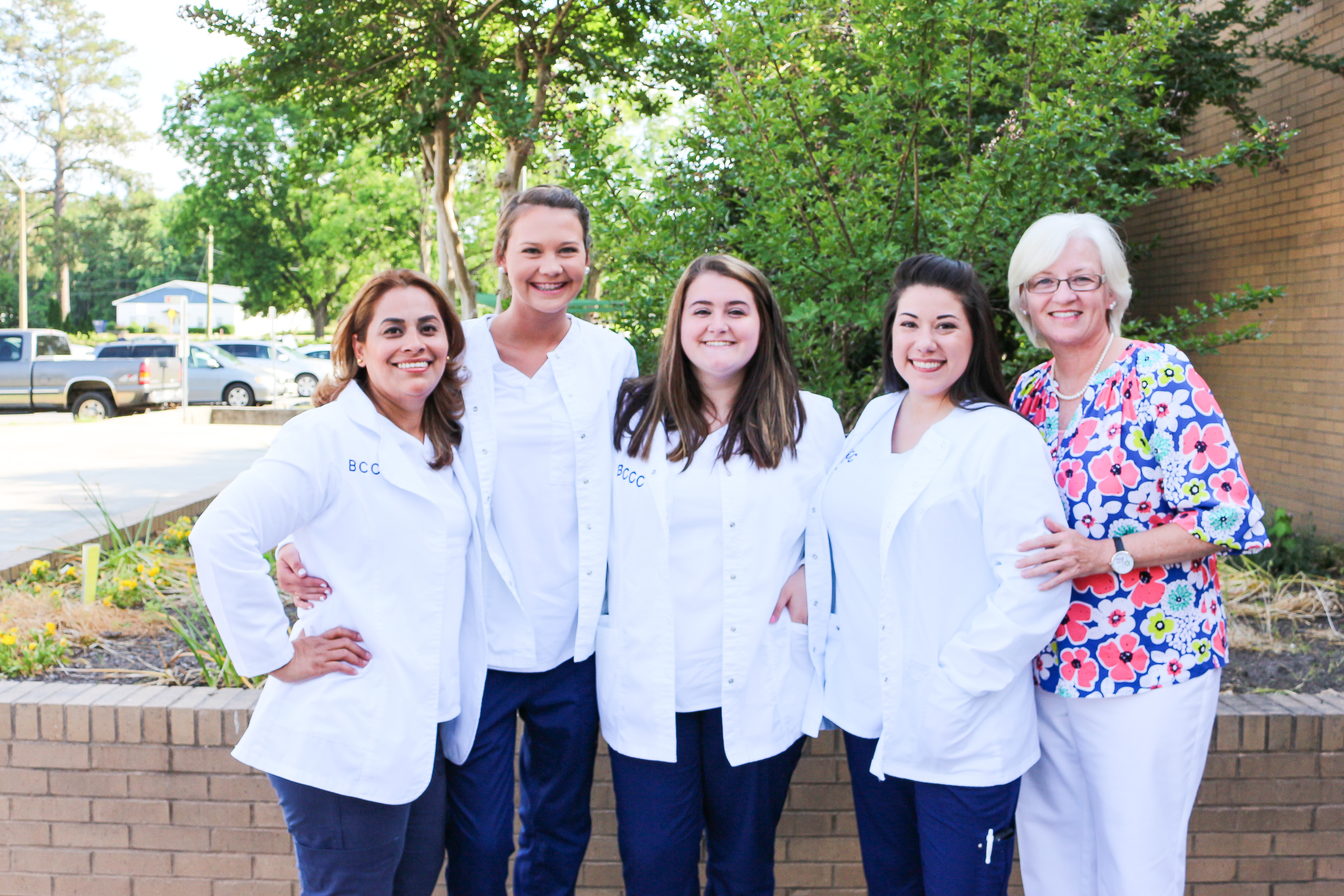 four students in white coats and one teacher in floral print
