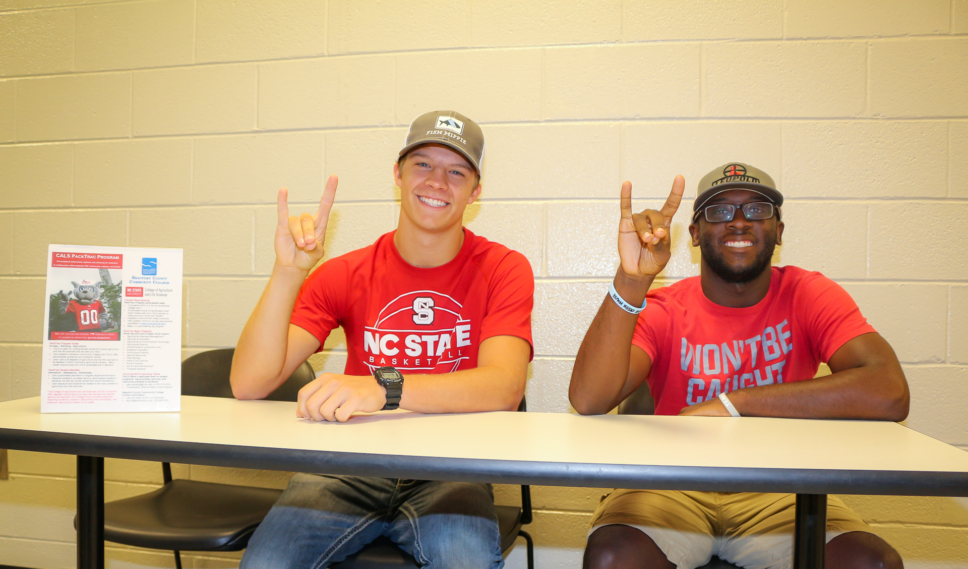 two students making Wolfpack sign.