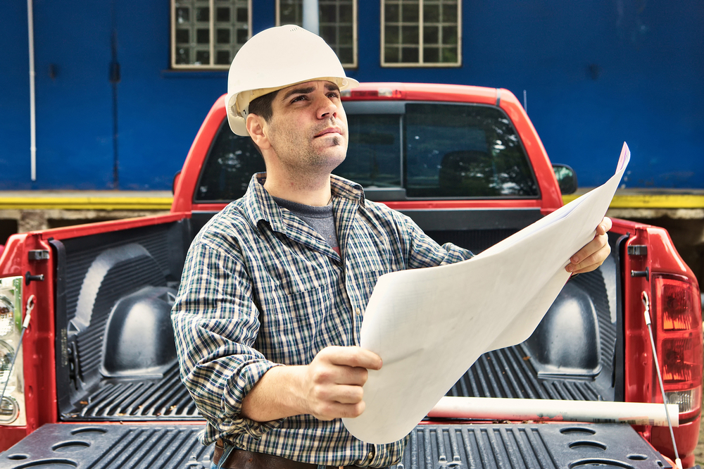 a person looking at blueprints near a truck