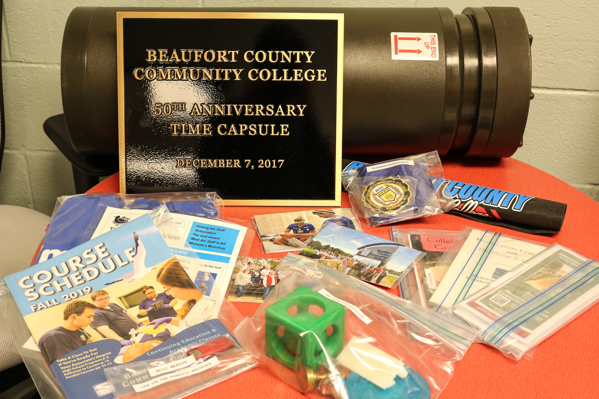 a time capsule with things in bags. a plaque that reads Beaufort County Community College 50th anniversary time capsule
