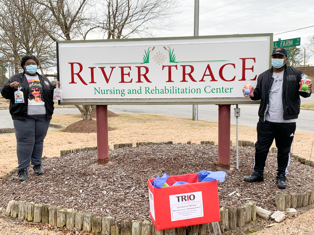 two students next to a sign that reads River Trace Nursing and Rehabilitation Center